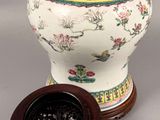 a vase with a lid sitting on a table next to a bowl