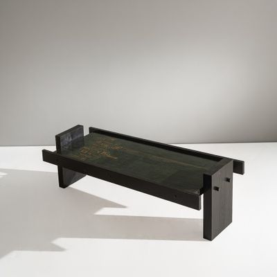 une table basse noire avec un plateau en verre posé sur un piètement blanc
