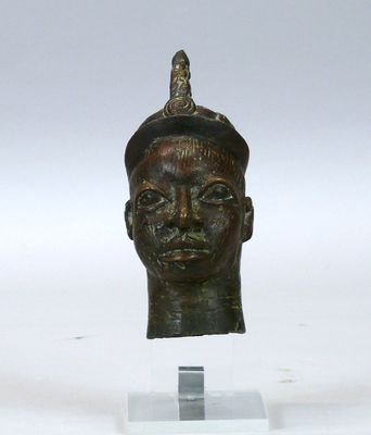 une image représentant une tête d'homme en bronze, avec un oiseau perché sur le sommet de sa tête