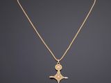 un collier en or avec un pendentif en forme de croix sur une chaîne