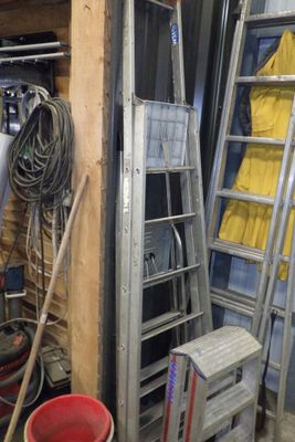 une échelle appuyée contre un mur, à côté d'un tas d'outils