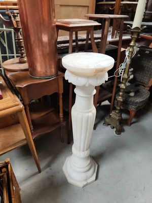 a white pedestal with a candle on top of it