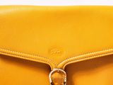 a close up of a yellow purse on a white surface