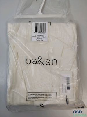 the white shirt is wrapped in plastic and has a bar and sh logo on it