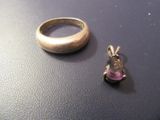 une bague en argent et une bague sertie d'une pierre rose posées sur une table