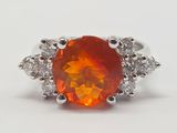 une bague sertie d'une opale de feu orange et de diamants, sur fond blanc