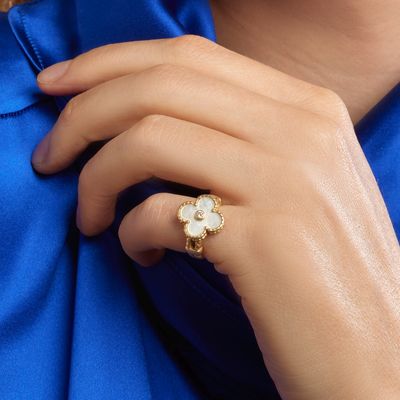 the woman is wearing a gold ring with a white flower on it