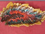 a picture of a colorful leaf shaped dish on a red surface