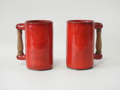 une paire de tasses rouges avec des anses en bois sur fond blanc