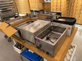 several stainless steel pans are lined up on a table in a warehouse