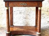 a small wooden table with a marble top on a brick floor