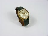 une montre en or avec un bracelet vert sur un fond blanc