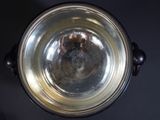 a silver bowl on a black table with a brown handle