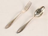two silver spoons and a fork on a table