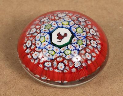 une boule en verre rouge ornée de fleurs blanches et bleues