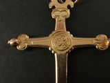 gold plated cross with a crown on top of it on a black surface