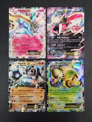 quatre cartes Pokémon différentes posées sur une table avec un fond noir