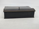 an old black box with a key on top of it on a white surface