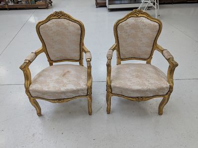 paire de chaises anciennes ornées de dorures et dotées d'accoudoirs rembourrés