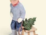 une figurine représentant un garçon portant un traîneau sur lequel est posé un arbre