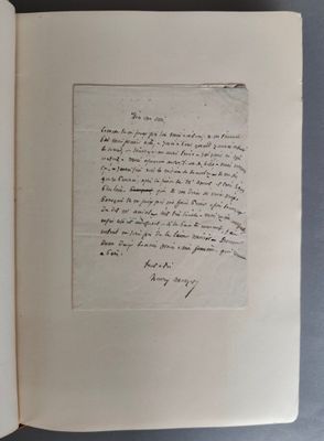 un livre ouvert, sur lequel repose une lettre manuscrite, posé sur une table