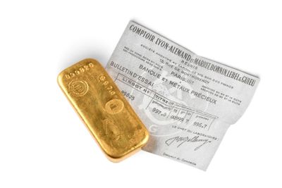 un gros plan d'un lingot d'or posé à côté d'un ticket de caisse sur une surface blanche