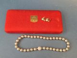 une photo représentant un collier et un étui rouge posés sur une table