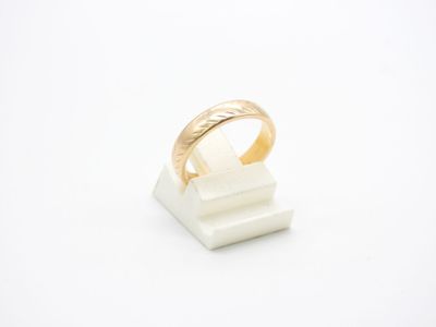 un gros plan d'une bague en or posée sur un bloc de marbre blanc