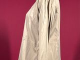 a beige jacket on a mannequin stand against a red background