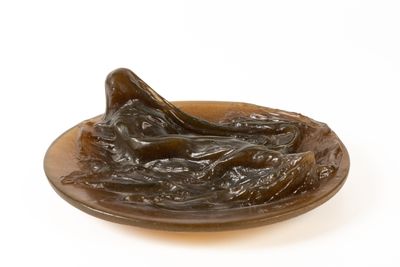une sculpture en bronze représentant une femme allongée sur une assiette
