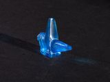 a small blue glass object on a black surface