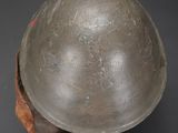 an old helmet on a wooden stand on a gray surface