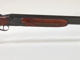 un vieux fusil de chasse au canon en bois, présenté sur un présentoir transparent