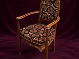 une vieille chaise dont l'assise est recouverte d'un tissu à motifs floraux sur fond violet