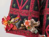 a woman wearing a colorful sweater with a flower on it