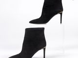 une paire de bottines en daim noir sur une semelle compensée transparente