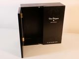 une boîte noire ouverte, dont la porte est ouverte, posée sur une surface blanche