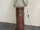 une lampe posée sur un socle en bois près d'un mur blanc