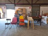 de nombreuses chaises et tables dans un entrepôt, avec un homme debout près d'une table