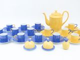 yellow and blue tea set with cups and saucers on a white surface