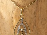 a close up of a gold necklace with a bird on it
