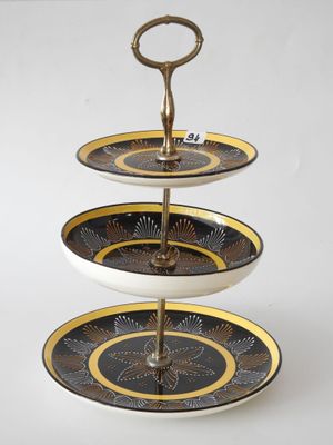 a three tiered cake stand with a gold and black design