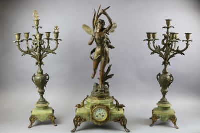 three candlesticks and a clock with a statue on top of them