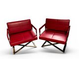 two red leather chairs sitting next to each other on a white surface