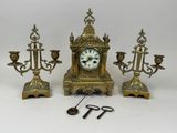 une horloge et trois bougeoirs placés les uns à côté des autres