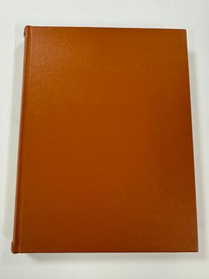 an orange book sitting on top of a table next to a white wall
