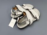 white and black sandals on a gray surface with a price tag