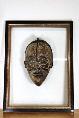 photo encadrée d'un masque en bois, dans un cadre en bois, posée sur une étagère