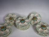 quatre fleurs en céramique blanches et vertes sont posées sur une surface blanche
