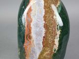 roche rayée de vert, d'orange et de blanc sur une surface grise